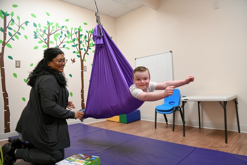 Patient Tyler working with his occupational therapist, smiling, flying like a superhero