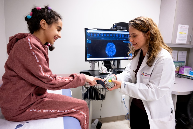 Pediatric neurologist Felicia Gliksman, D.O., and a patient looking at an anatomical model of a brain.
