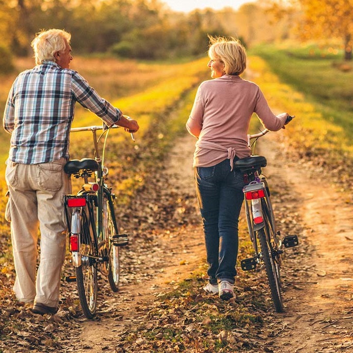 man and woman walking with bikes in a field