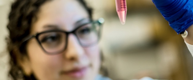 close up scientist looking at a vile