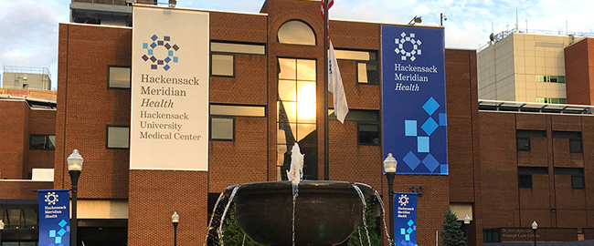 Hackensack Meridian Health hospital exterior with fountain and flags