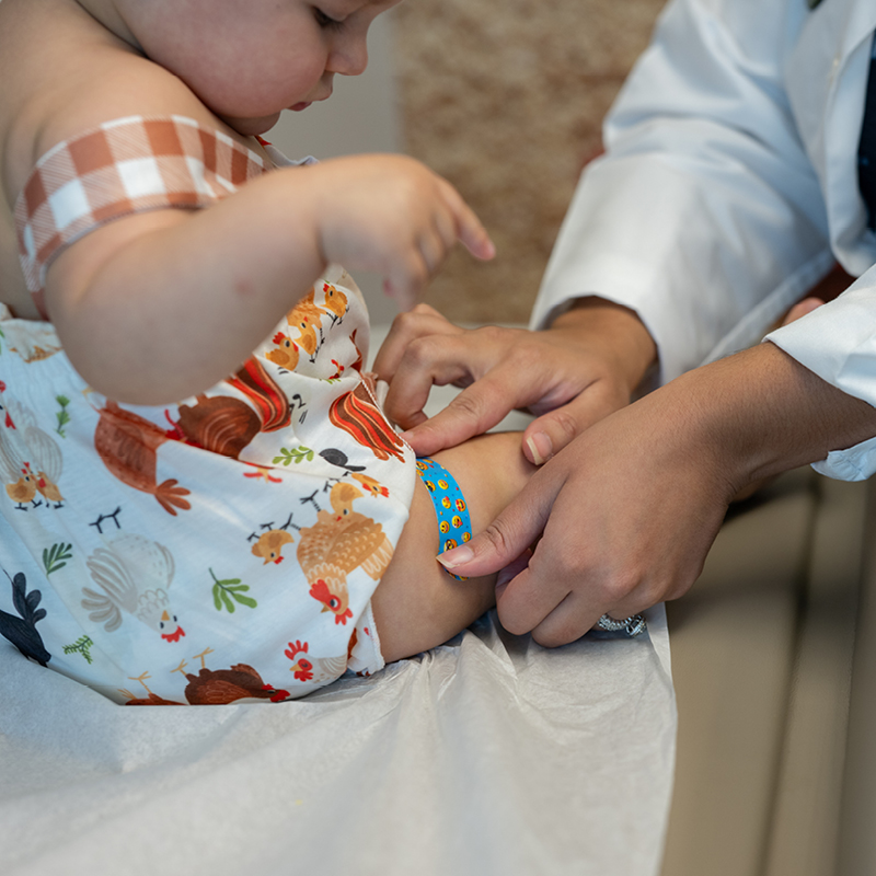 Hackensack Meridian Health pediatrician applying a bandaid to baby