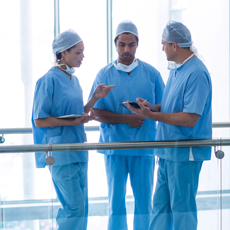 Team of surgeons in blue scrubs discussing patient care in a hospital.
