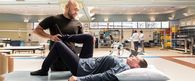 physical therapist bending patients knee