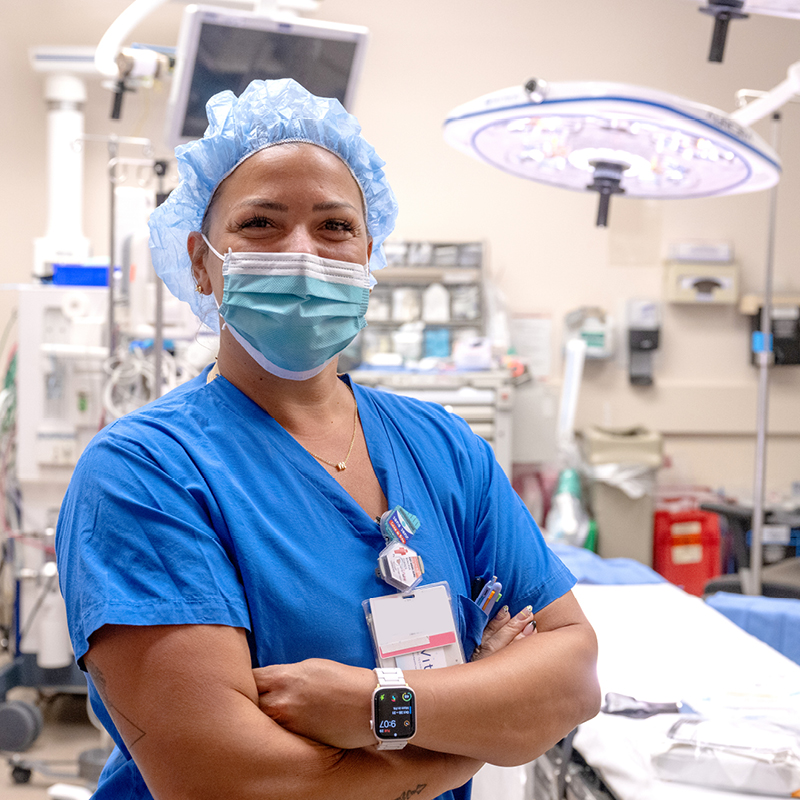 Healthcare professional in scrubs and mask in an operating room.