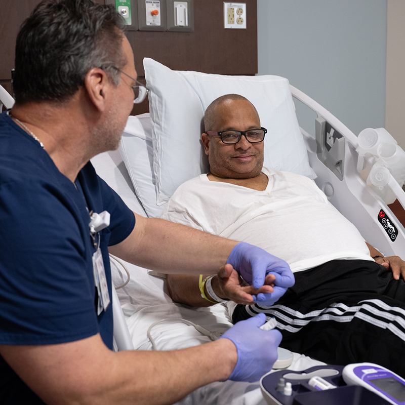 Male Patient in hospital bed with mail nurse at his side