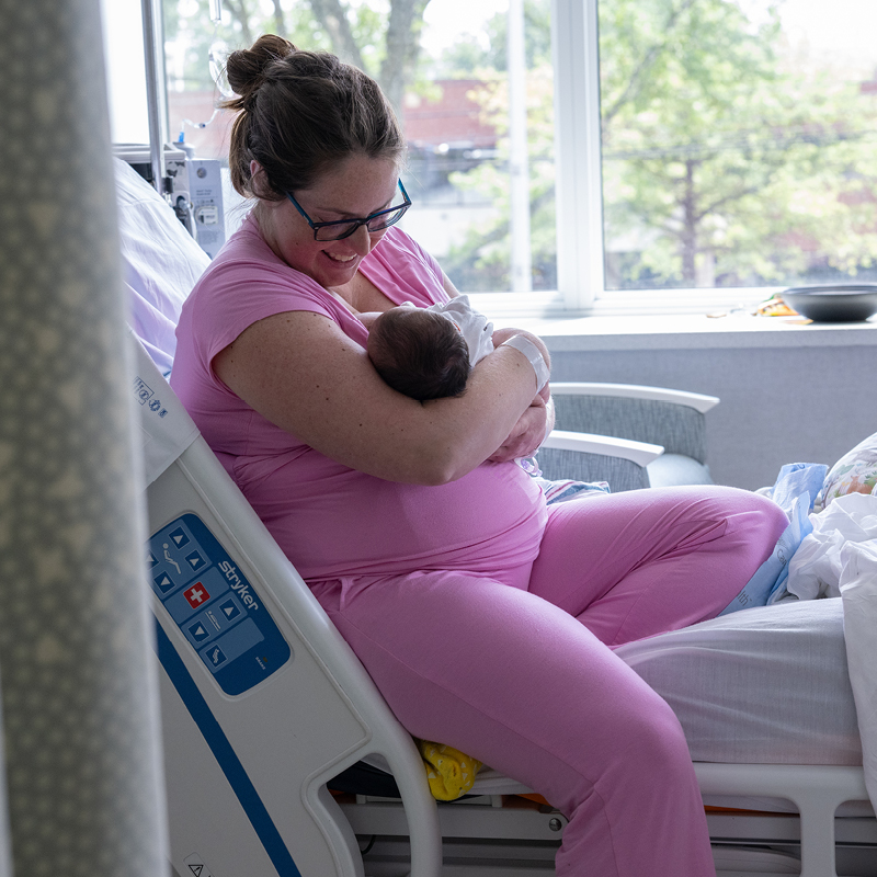 Mother holding her newborn baby in a hospital room.