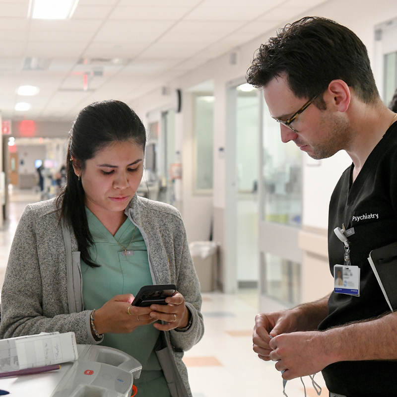 Healthcare professional and visitor reviewing information in a hospital hallway.