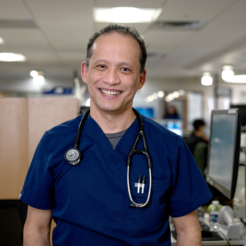 Healthcare professional in scrubs with a stethoscope in a hospital setting.
