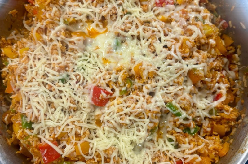 A pan of deconstructed stuffed peppers is covered in melty cheese.