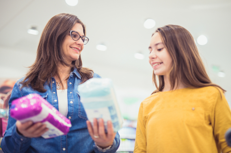 Mother and daughter choose sanitary pads to buy at the store.