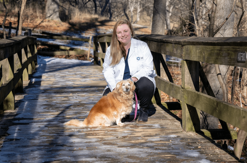 Courtney Cunningham, M.D, kneels outside next to her dog while holding the leash.