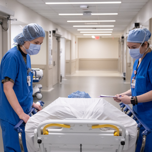Two doctors with a patient in a transport bed, in the hallway, on the way to an organ transplant procedure.