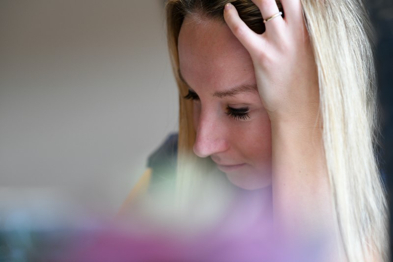 young Caucasian woman grabs head with fear of concussion