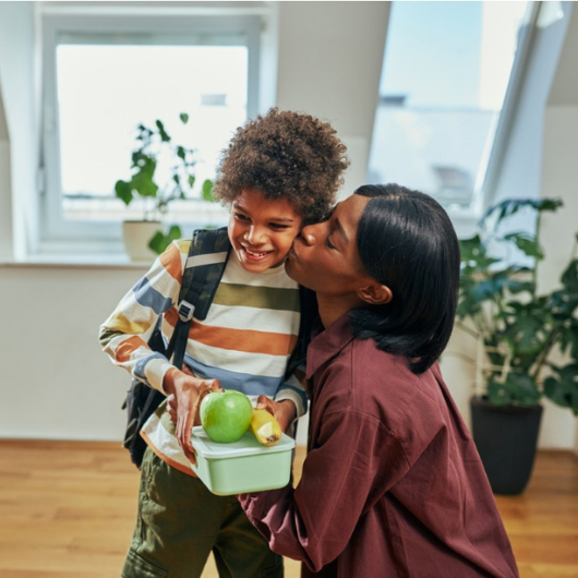 Mom kissing young child going to school