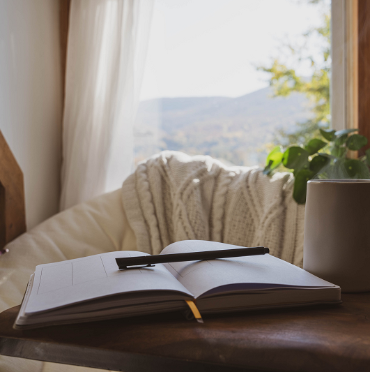 A cozy mental health break with an open journal, pen and cup of tea.