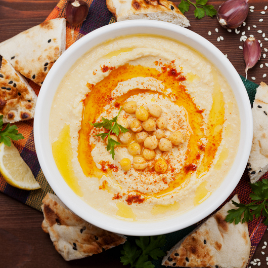Hummus with lemon on a wooden table, top view.