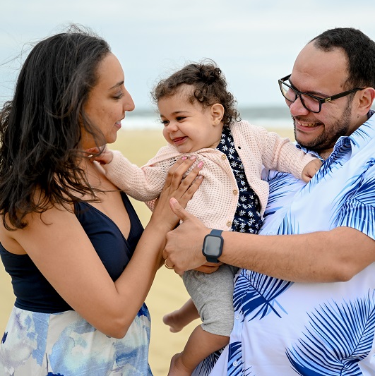 Dr. Andrew Habib, his wife and new baby smiling on the beach.