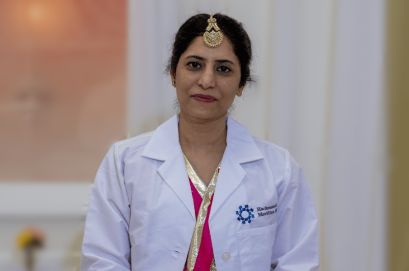 Neha Bangia, M.D., sits on the ground and smiles at the camera.