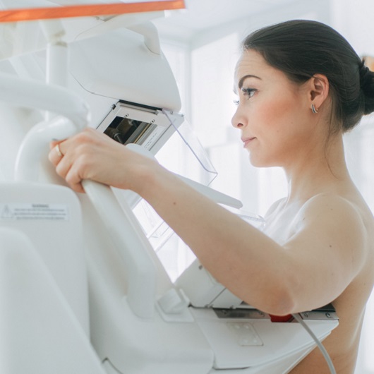 Side view of a woman in her 40's getting a mammogram for early breast cancer detection.