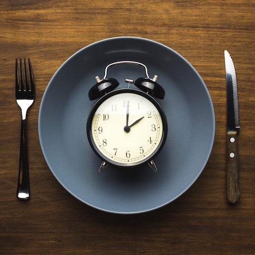 plate with clock laying on it, fork and knife