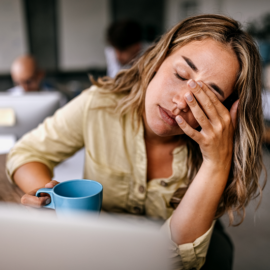 Young woman rubbing her eyes, suffering from a migraine while working from home