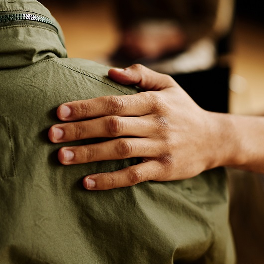 A hand on a person's back, a friend offering comfort; representative of support for mental health conditions and addiction 