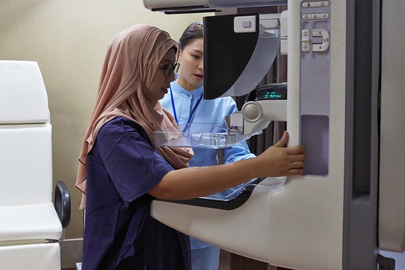 Woman standing in front of a mammogram machine for diagnostic imaging of her breast
