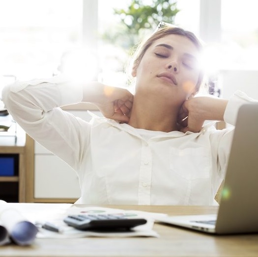 woman sitting at home office grabbing neck and feeling pain