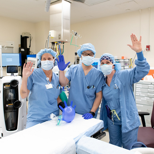 pediatric surgical team smiling and waving from the operating room