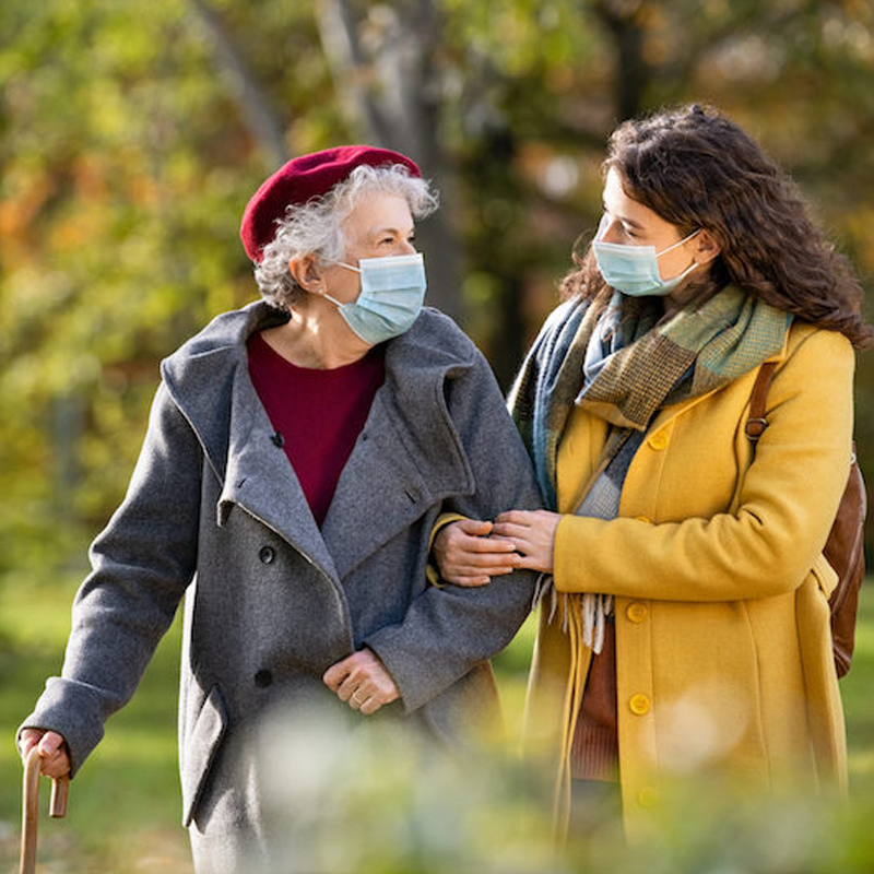Woman in yellow coat holding arm of older woman in gray jacket