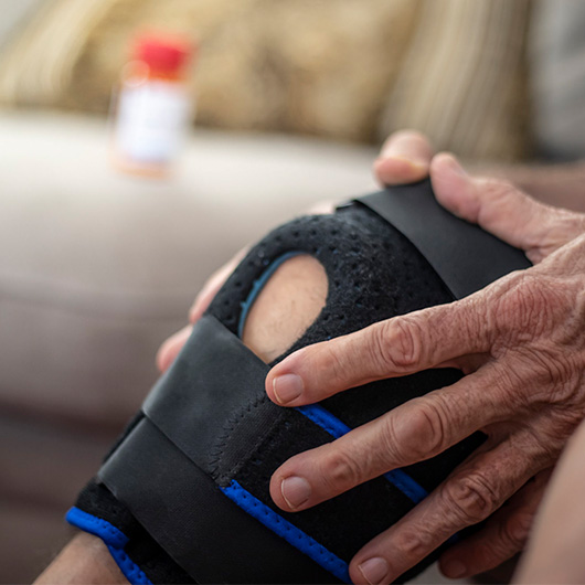 Hand holding knee in brace