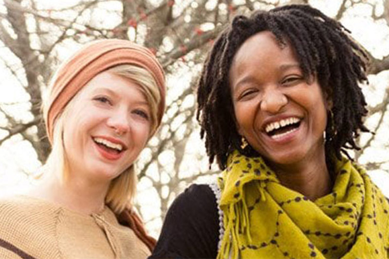 Two women smiling outside on a sunny day.