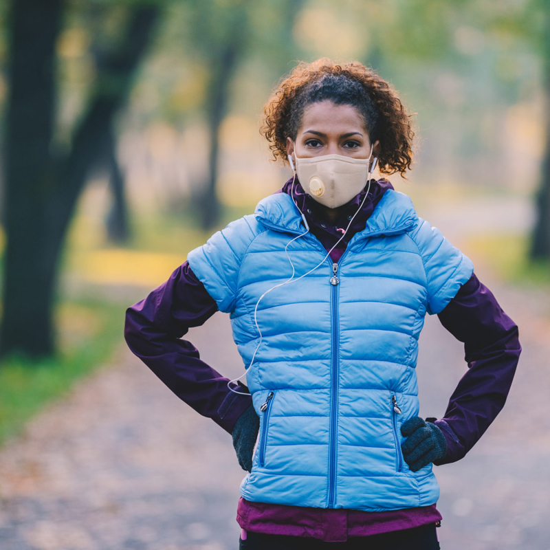Woman in blue vest wearing a mask at the park