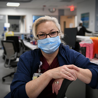 A nurse, behind a desk, smiling at an urgent care