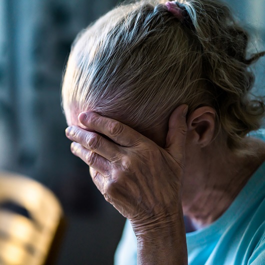 Sad senior woman, with her face in her hands, dealing with loss and grief.