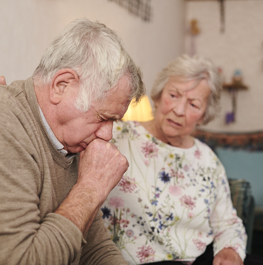 senior man with wife at home coughing badly