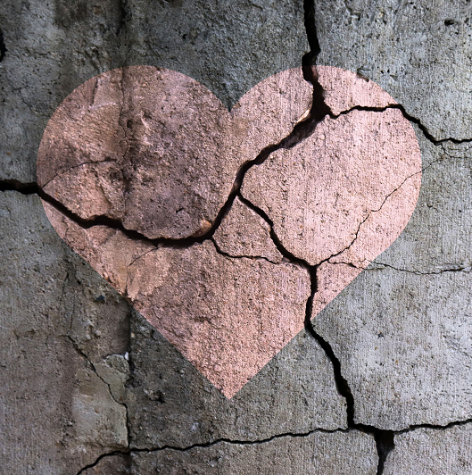 A broken heart; a drawing of a heart on a cracked wall. 