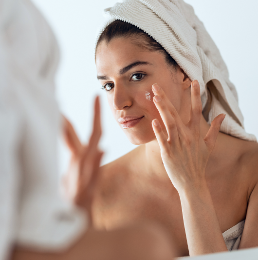 Young woman in the bathroom treating her acne with toothpaste. 