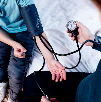 Close up view of a doctor taking a child's blood pressure. Child wearing blood pressure cuff.