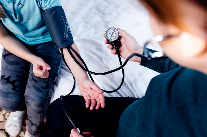 Close up view of a doctor taking a child's blood pressure. Child wearing blood pressure cuff.