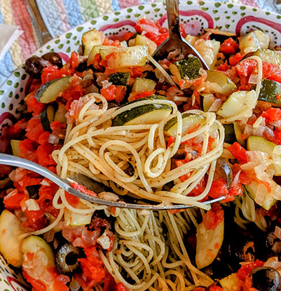 a pasta dish with garden vegetables and pesto