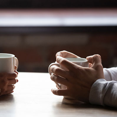 Close up view of a couple holding coffee cups having a serious conversation about STD testing.