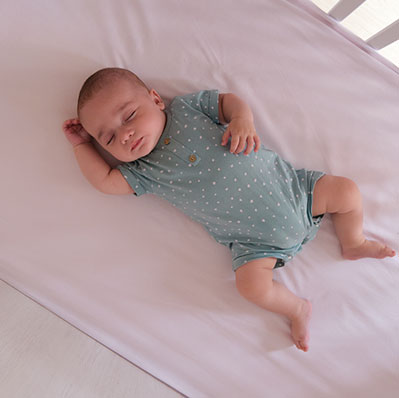 Small baby sleeping peacefully and safely in their crib.