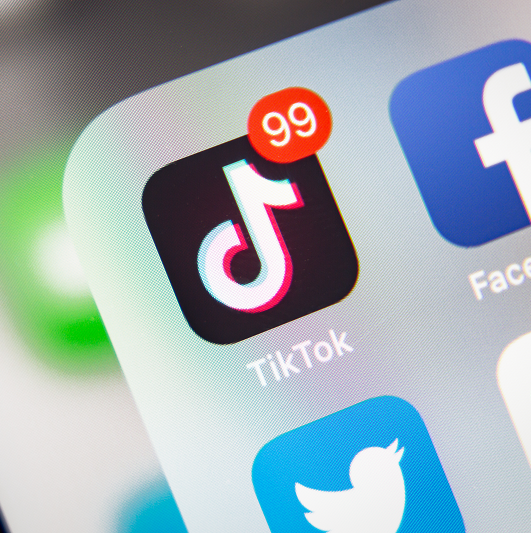 Close up view of a phone with the TikTok app and there are 99 notifications.