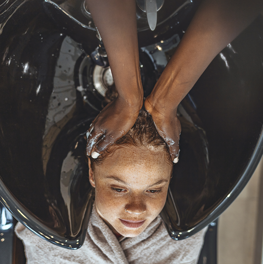 Young woman getting her hair done at a salon - chemical hair straightening.