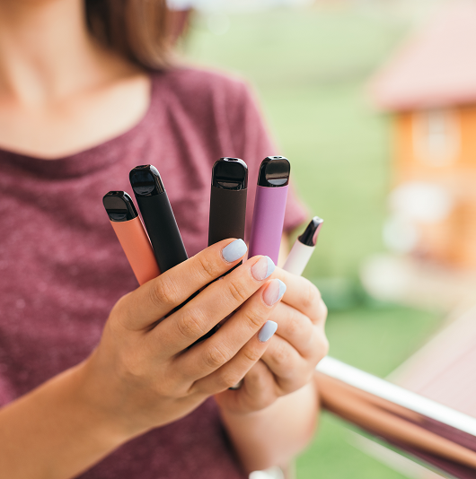 Young woman holding a bunch of e-cigarettes, vapes, or Jules. Toxic chemicals.