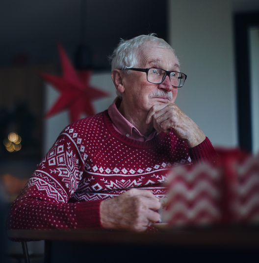 Elderly man with dementia sits in his home waiting for family to come during the holidays.