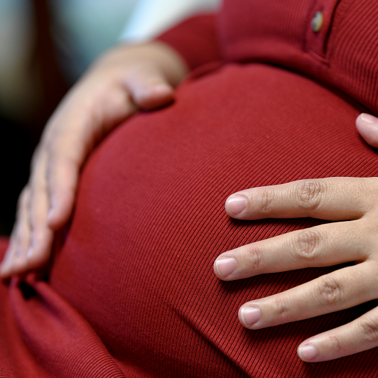woman's hands holding her pregnant belly, feeling contractions, braxton hicks or labor