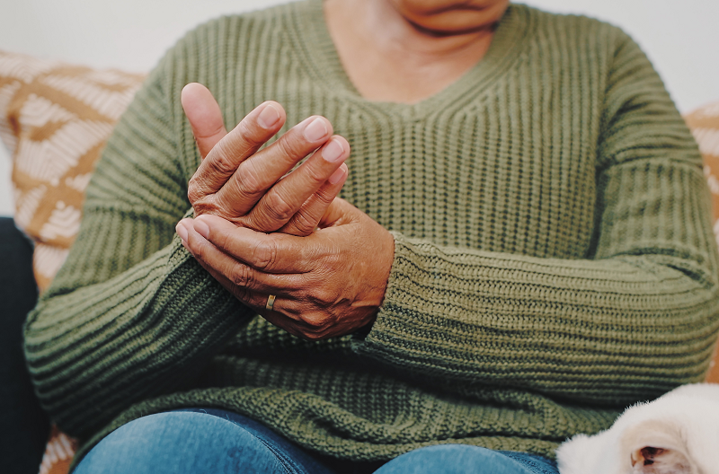 Woman holding her hand, aching from arthritis, possibly from COVID